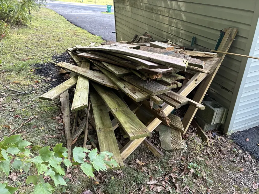 A wood debris pile beside a home, ready for A&P junk removal